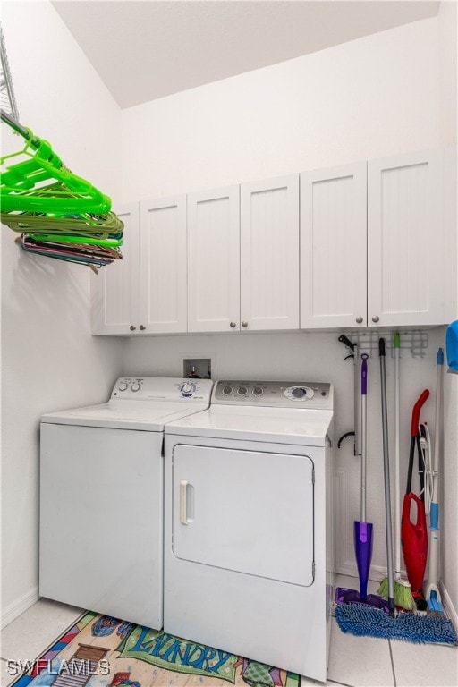 laundry area with light tile patterned floors, cabinets, and washer and dryer