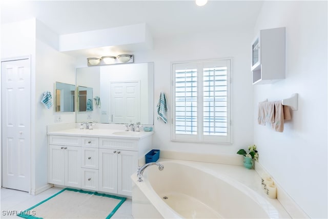 bathroom with a washtub, vanity, and tile patterned floors