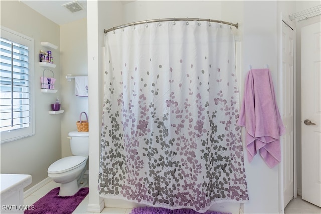 bathroom with a shower with shower curtain, tile patterned floors, and toilet