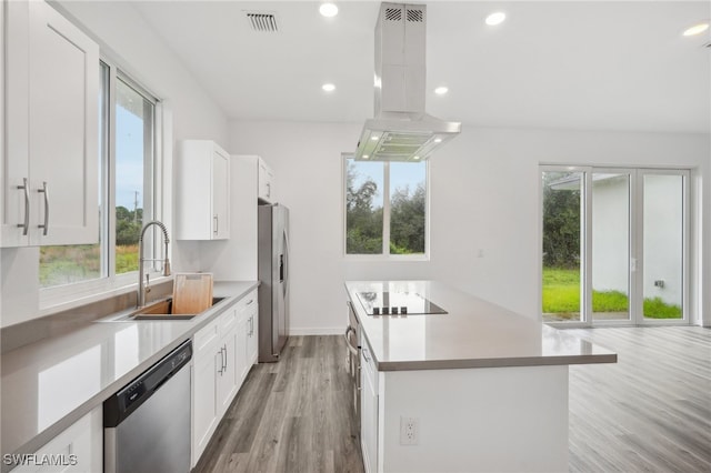 kitchen featuring island exhaust hood, appliances with stainless steel finishes, sink, light hardwood / wood-style floors, and white cabinetry