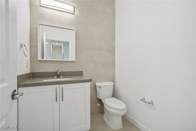 bathroom featuring vanity, tile walls, and toilet