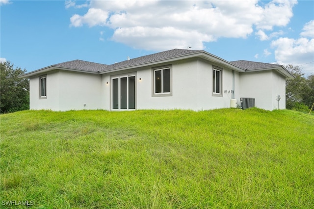 rear view of property with cooling unit and a yard