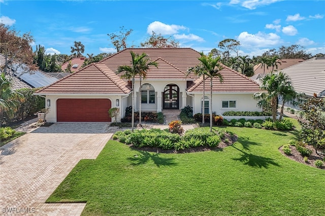 mediterranean / spanish-style home featuring a front lawn and a garage