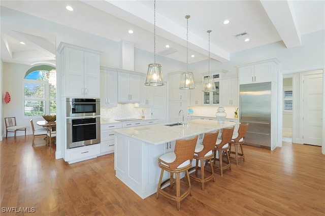 kitchen with white cabinets, appliances with stainless steel finishes, decorative backsplash, and beam ceiling