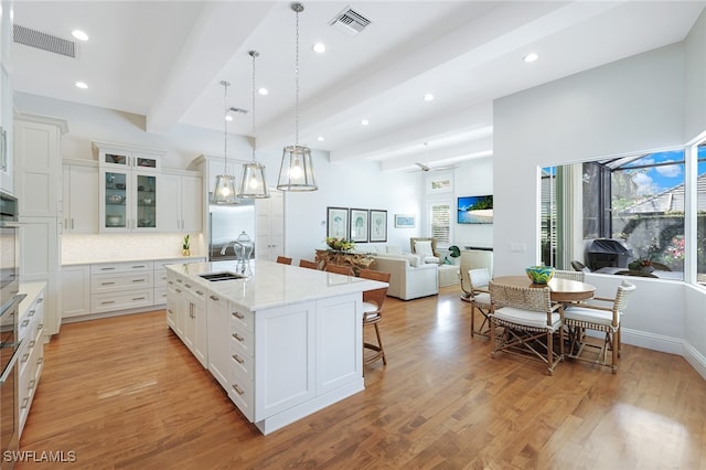 kitchen with white cabinetry, light hardwood / wood-style flooring, and a kitchen island with sink