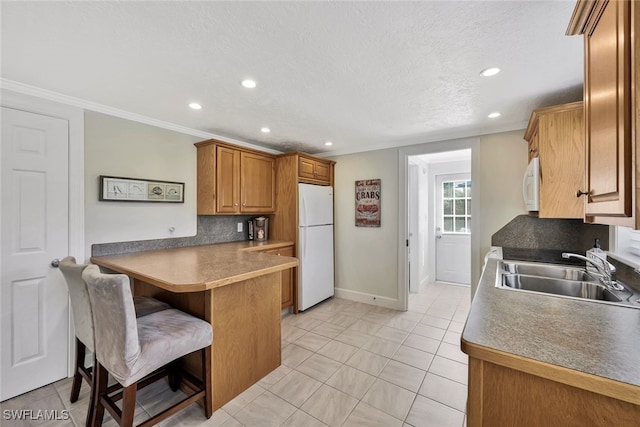 kitchen featuring sink, kitchen peninsula, ornamental molding, a breakfast bar area, and white appliances