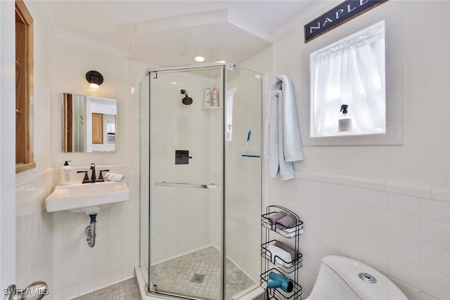 bathroom featuring tile walls, crown molding, toilet, and a shower with shower door