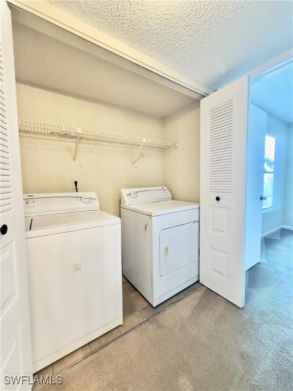 washroom featuring light carpet, independent washer and dryer, and a textured ceiling