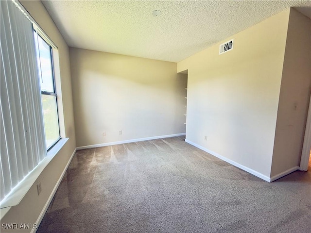 carpeted spare room featuring a textured ceiling