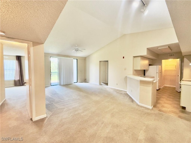 unfurnished living room featuring light colored carpet, vaulted ceiling, and ceiling fan