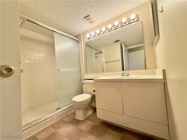 bathroom with tile patterned floors, a textured ceiling, vanity, a shower with door, and toilet