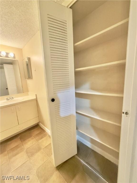 interior space with tile patterned flooring, vanity, and a textured ceiling