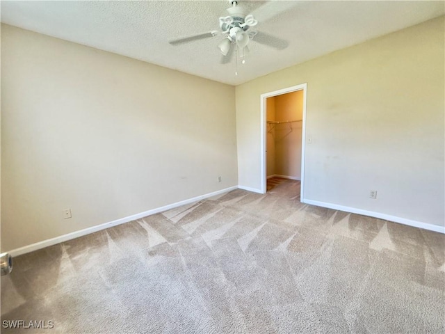 unfurnished bedroom with light carpet, a textured ceiling, ceiling fan, a spacious closet, and a closet