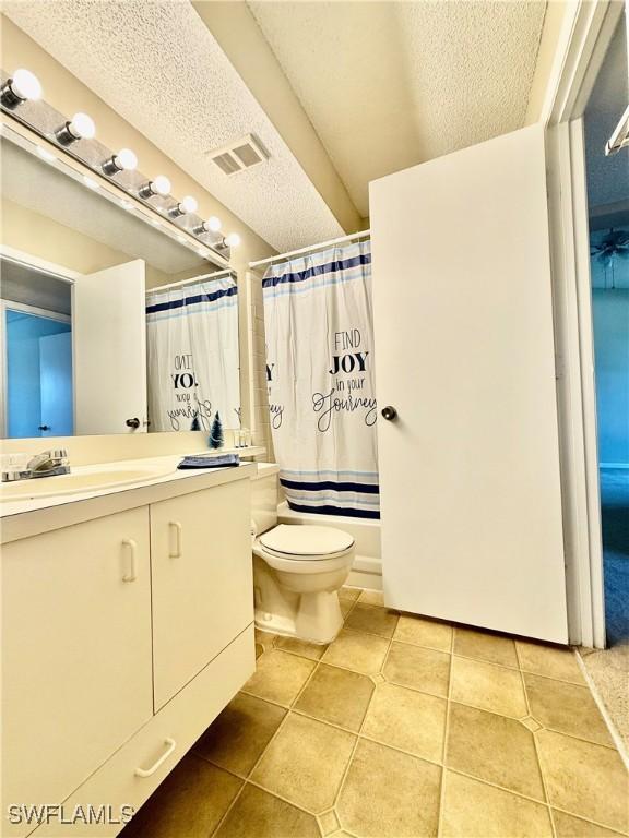 full bathroom featuring shower / bath combo, tile patterned floors, vanity, a textured ceiling, and toilet