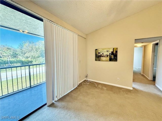 carpeted empty room with a textured ceiling, plenty of natural light, and vaulted ceiling