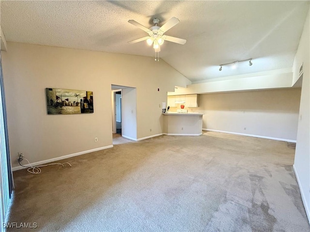 spare room with ceiling fan, a textured ceiling, carpet flooring, baseboards, and vaulted ceiling