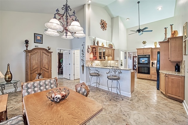 dining area with ceiling fan with notable chandelier and high vaulted ceiling