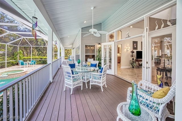 wooden terrace with a pool with hot tub, glass enclosure, ceiling fan, and a patio area