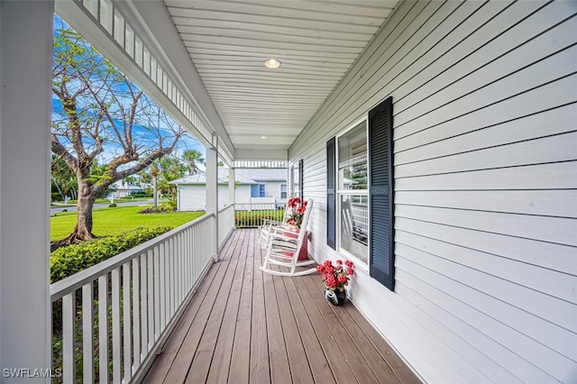 wooden deck with a garage, a yard, and covered porch