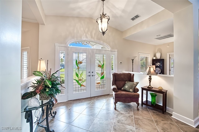 tiled entrance foyer with french doors and a notable chandelier