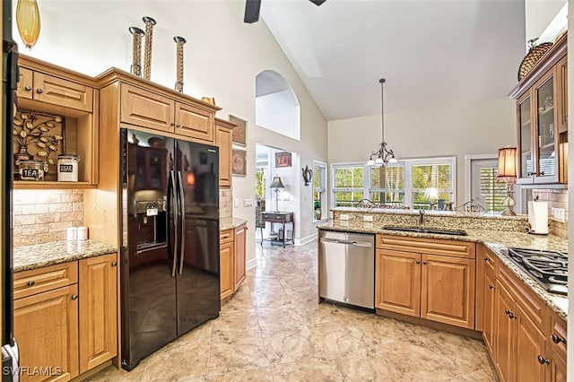 kitchen with sink, appliances with stainless steel finishes, light stone countertops, high vaulted ceiling, and hanging light fixtures