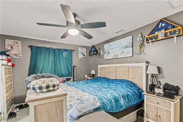 bedroom with a textured ceiling, light tile patterned floors, and ceiling fan