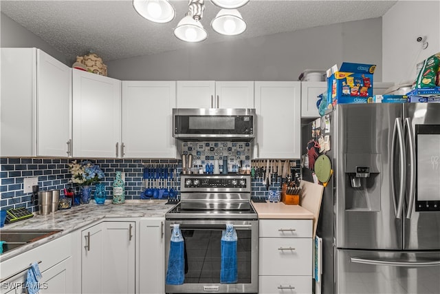 kitchen featuring appliances with stainless steel finishes, decorative backsplash, lofted ceiling, and white cabinets