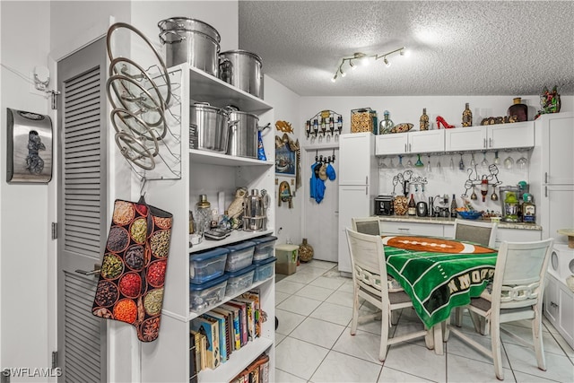 kitchen featuring white cabinetry, lofted ceiling, a textured ceiling, and light tile patterned floors