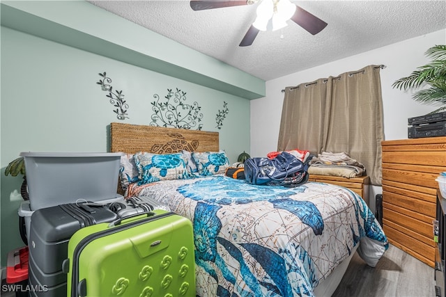 bedroom with hardwood / wood-style flooring, ceiling fan, and a textured ceiling