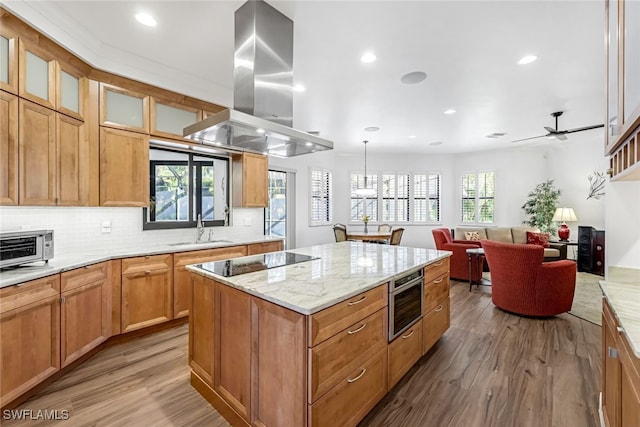 kitchen with ceiling fan, sink, black electric cooktop, island range hood, and a kitchen island