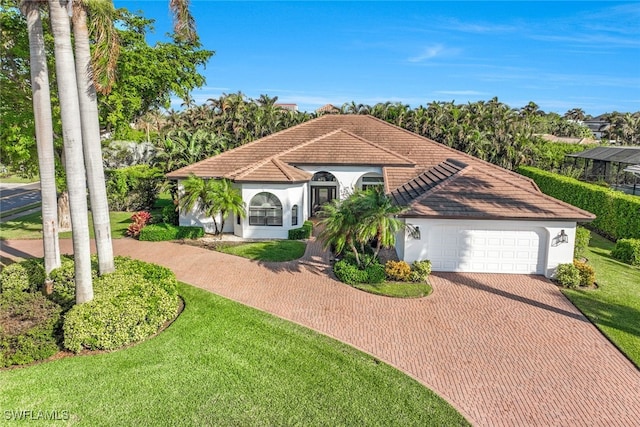 mediterranean / spanish-style home with a garage and a front lawn