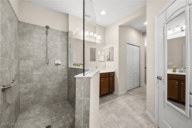 bathroom featuring tile patterned flooring, vanity, and a tile shower