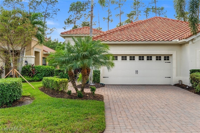 mediterranean / spanish-style house featuring a garage and a front lawn