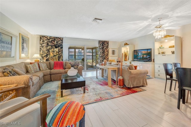 living room featuring light hardwood / wood-style floors, ceiling fan, and a textured ceiling