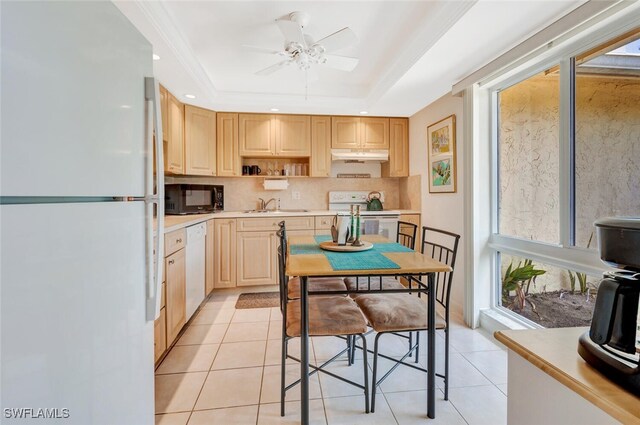 kitchen with a wealth of natural light, light brown cabinetry, white appliances, and a tray ceiling