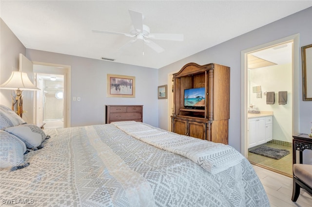 bedroom with light hardwood / wood-style floors, ceiling fan, and connected bathroom