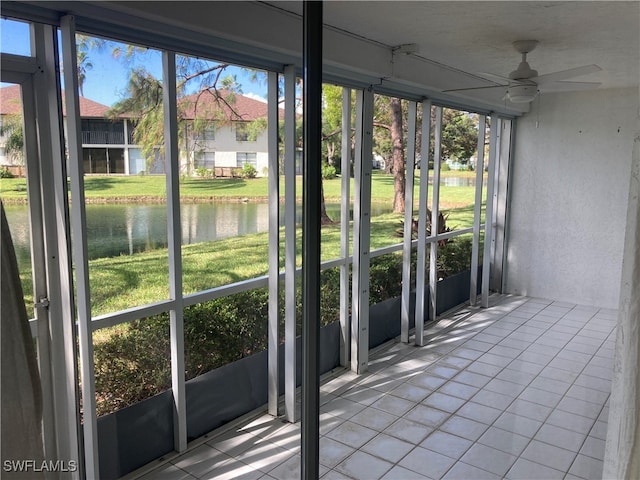 unfurnished sunroom with ceiling fan and a water view