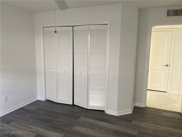 unfurnished bedroom featuring a closet, dark wood-type flooring, and ceiling fan