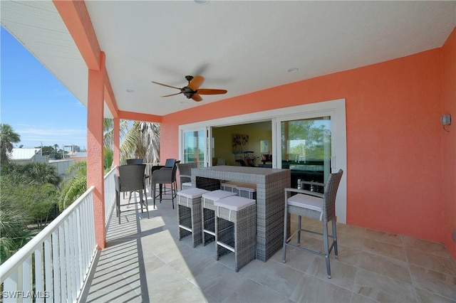 view of patio with outdoor dry bar, a balcony, and a ceiling fan