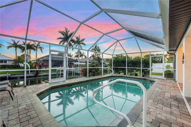 pool at dusk featuring a patio and a lanai