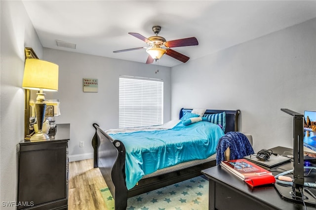 bedroom with ceiling fan, light wood finished floors, visible vents, and baseboards