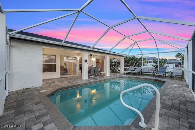 outdoor pool with a patio area, glass enclosure, and ceiling fan