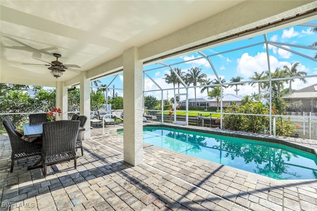 outdoor pool featuring a ceiling fan, glass enclosure, and a patio