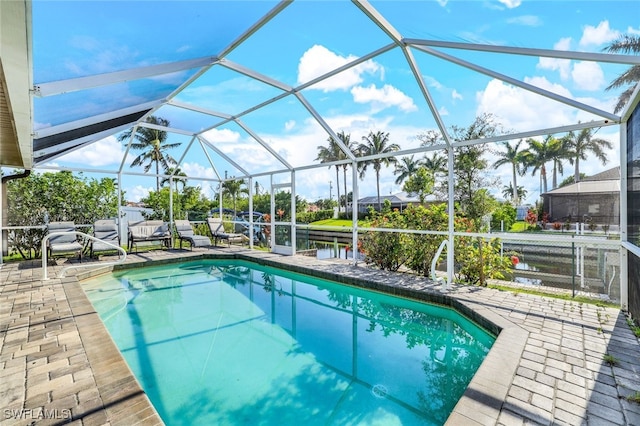 pool with a patio area, glass enclosure, and a water view