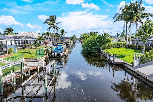 view of dock with a water view, boat lift, a residential view, and a yard