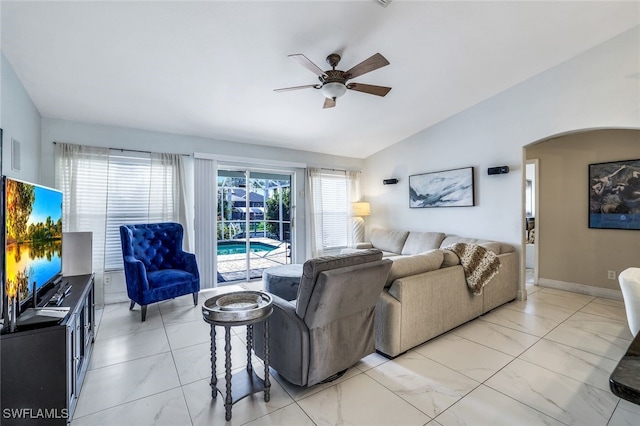 living room with vaulted ceiling, ceiling fan, arched walkways, and baseboards