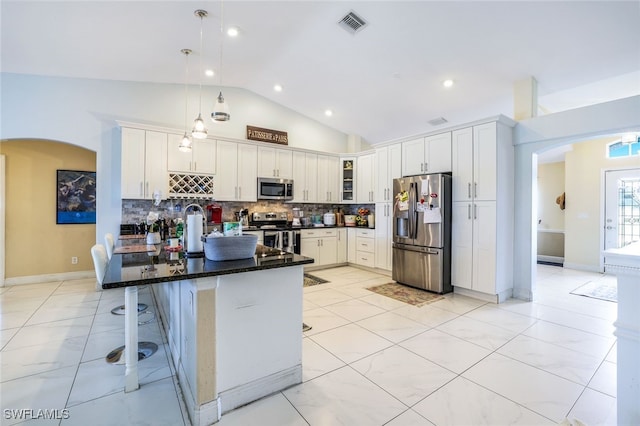 kitchen with pendant lighting, appliances with stainless steel finishes, glass insert cabinets, white cabinets, and vaulted ceiling