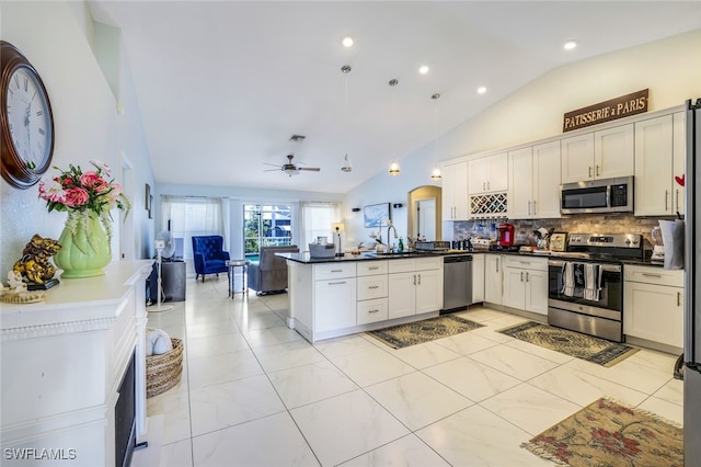 kitchen featuring a peninsula, a sink, hanging light fixtures, appliances with stainless steel finishes, and dark countertops