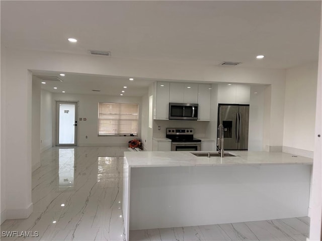 4562 Tennyson Dr, North Fort Myers, FL 33903 - kitchen featuring appliances with stainless steel finishes, modern cabinets, white cabinets, recessed lighting, and light marble finish flooring