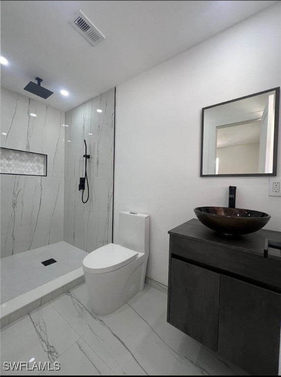 bathroom with toilet, vanity, and a tile shower